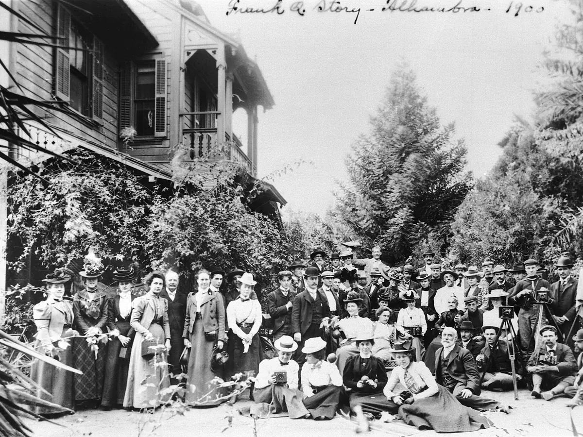 Black-and-white photo of a large group posed outside the Frank Q. Story residence in Alhambra around 1900